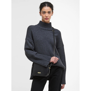 Naisella on musta olkahihnallinen Barbour Daphne -nahkalaukku.