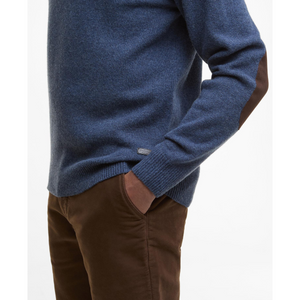 Kuvan sinisessä miesten villaneuleessa on ruskeat, nahkaiset kyynärpaikat sekä nahkainen logomerkki helmassa.