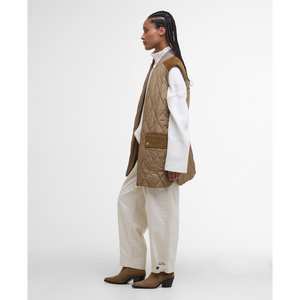 Tässä midimittaisessa tikatussa liivissä on tyylikkäät vakosamettiset yksityiskohdat olkapäillä ja etutaskuissa.