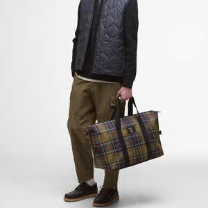 Kuvassa mies kantaa Barbourin Tartaanikuvioista viikonloppulaukkua.