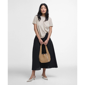 Naisella on päällään vaalean beige Barbour Ava Top t-paita. T-paita sopii hyvin asuksi hameen kanssa.