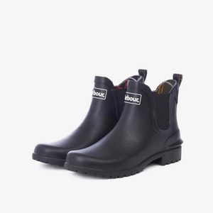 Kuvassa on mustat, lyhytvartiset, Chelsea-tyyppiset naisten kumisaappaat joissa on edessä valkoinen Barbour-logo.