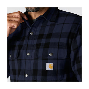 Lähikuvassa on Carhartt Flannel Sherpa Lined paitatakki. Takissa on Carhartt logo rinnassa ja rinnassa on myös taskut jotka voi sulkea napeilla.