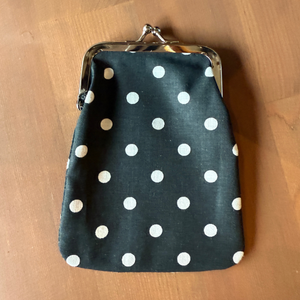 Kuvassa on musta kangaskukkaro jossa on valkoisia pilkkuja.