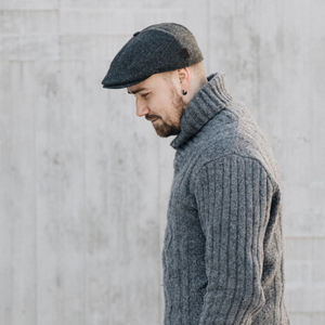 Kuvassa miehen päässä on klassinen, kuusipaneelinen flat cap jonka keskellä on nappi.