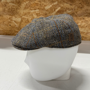 Kuvassa on Harris Tweed kankaasta kudottu Flat Cap Rocky Gen beigen ja sinisen eri sävyissä.