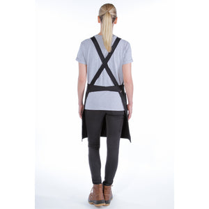 Kuvassa on Carharttin musta Duck Canvas esiliina takaa päin kuvattuna naisen päällä valkoisella pohjalla.