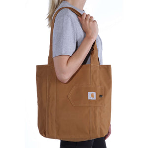Kuvassa naisella on käytössä Carhartt Essentials Tote laukku. Laukku on värissä Carhartt Brown.