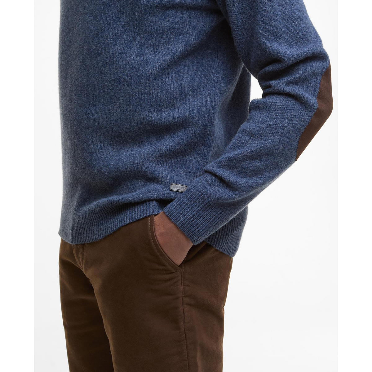 Kuvan sinisessä miesten villaneuleessa on ruskeat, nahkaiset kyynärpaikat sekä nahkainen logomerkki helmassa.