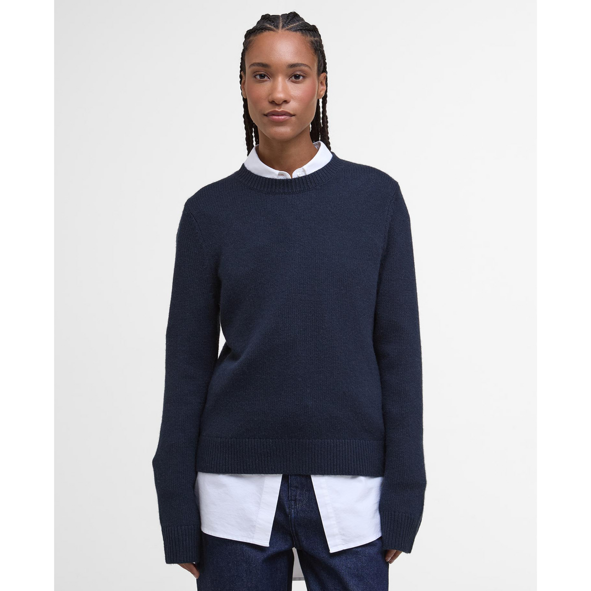 Kuvassa naisella on kauluspaidan päällä tummansininen Barbour Woodhouse villasekoiteneule.