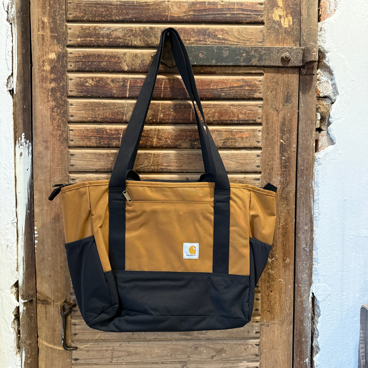 Kuvassa on Carhartt Classic Laptop Tote läppärilaukku joka on ruskea ja siinä on musta alaosa sekä musta kantohihna.