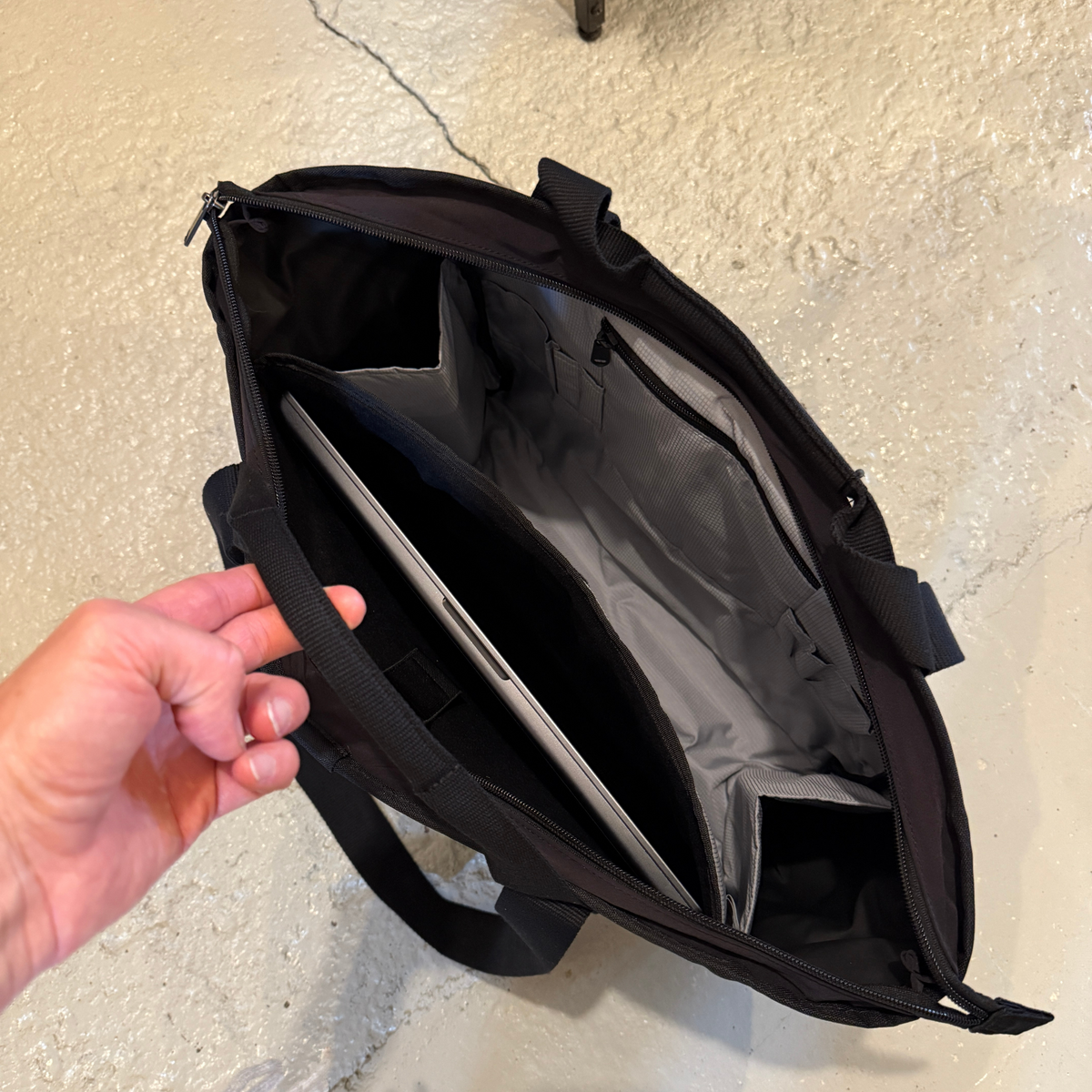 Kuvassa on Carhartt Classit Laptop Tote läppärilaukku sisältä. Laukun sisällä on tietokoneelle oma tasku sekä isompi tasku johon saa muita tavaroita. Lisäksi on myös pieni vetoketjutasku. 