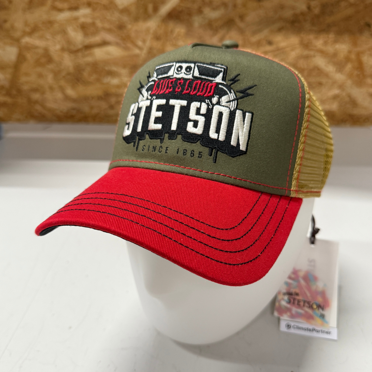 Kuvassa on puna-vihreä-keltainen Stetson -lippis jossa on etuosassa kuva kaiuttimista ja teksti Live&Loud.