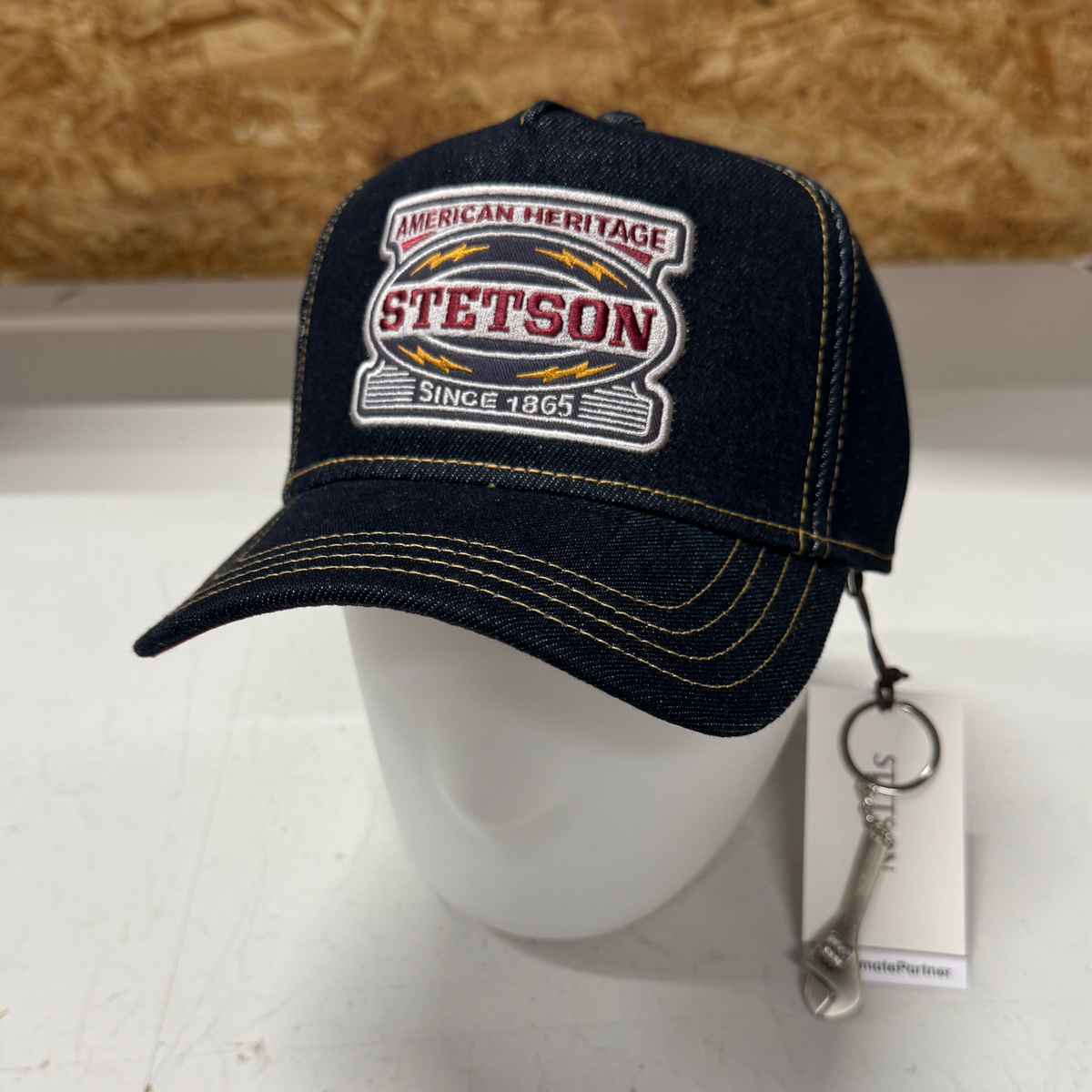 Kuvassa on farkkukankainen Stetson Garage -sarjan Trucker Cap jossa mukana minikokoinen metallinen jakoavain.