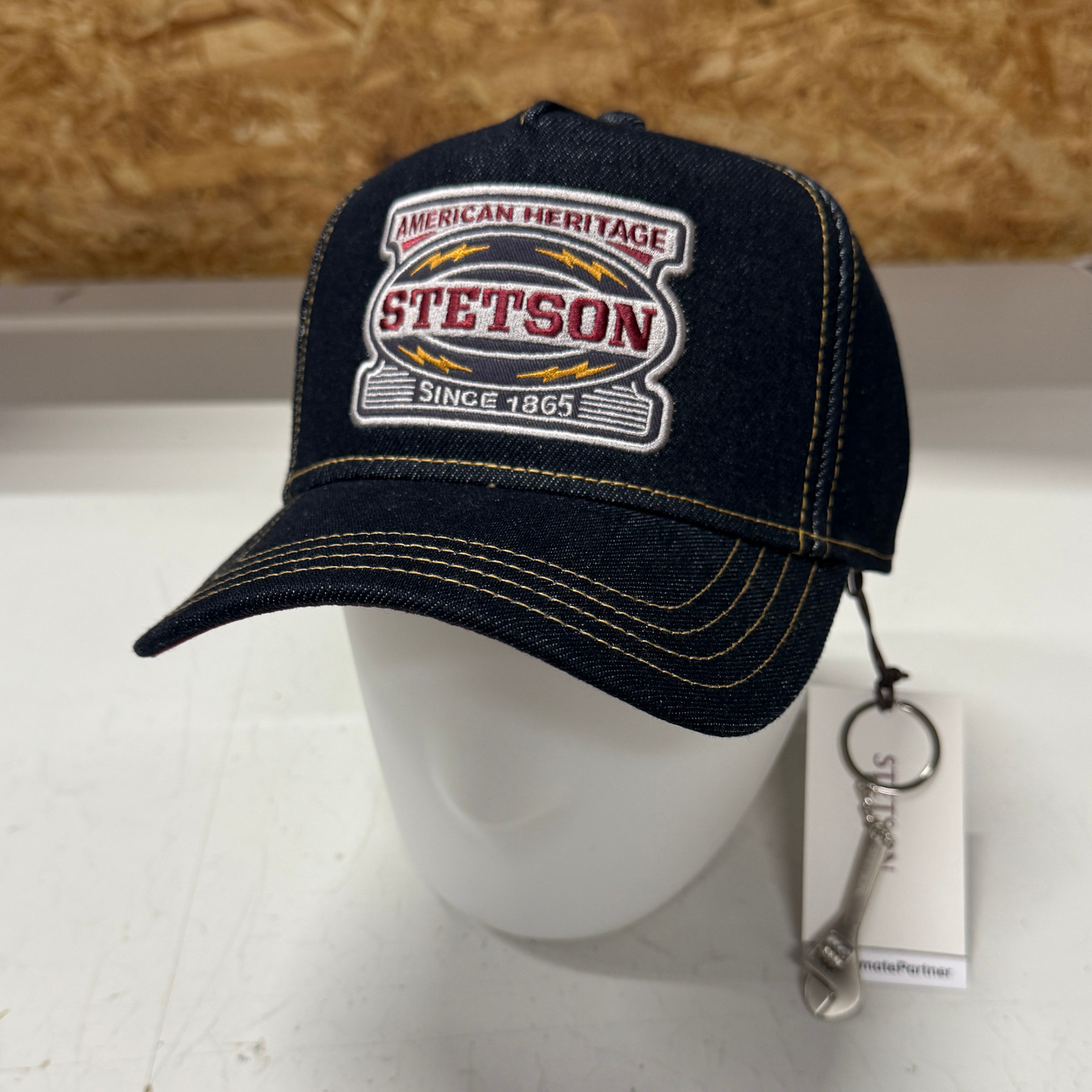 Kuvassa on farkkukankainen Stetson Garage -sarjan Trucker Cap jossa mukana minikokoinen metallinen jakoavain.