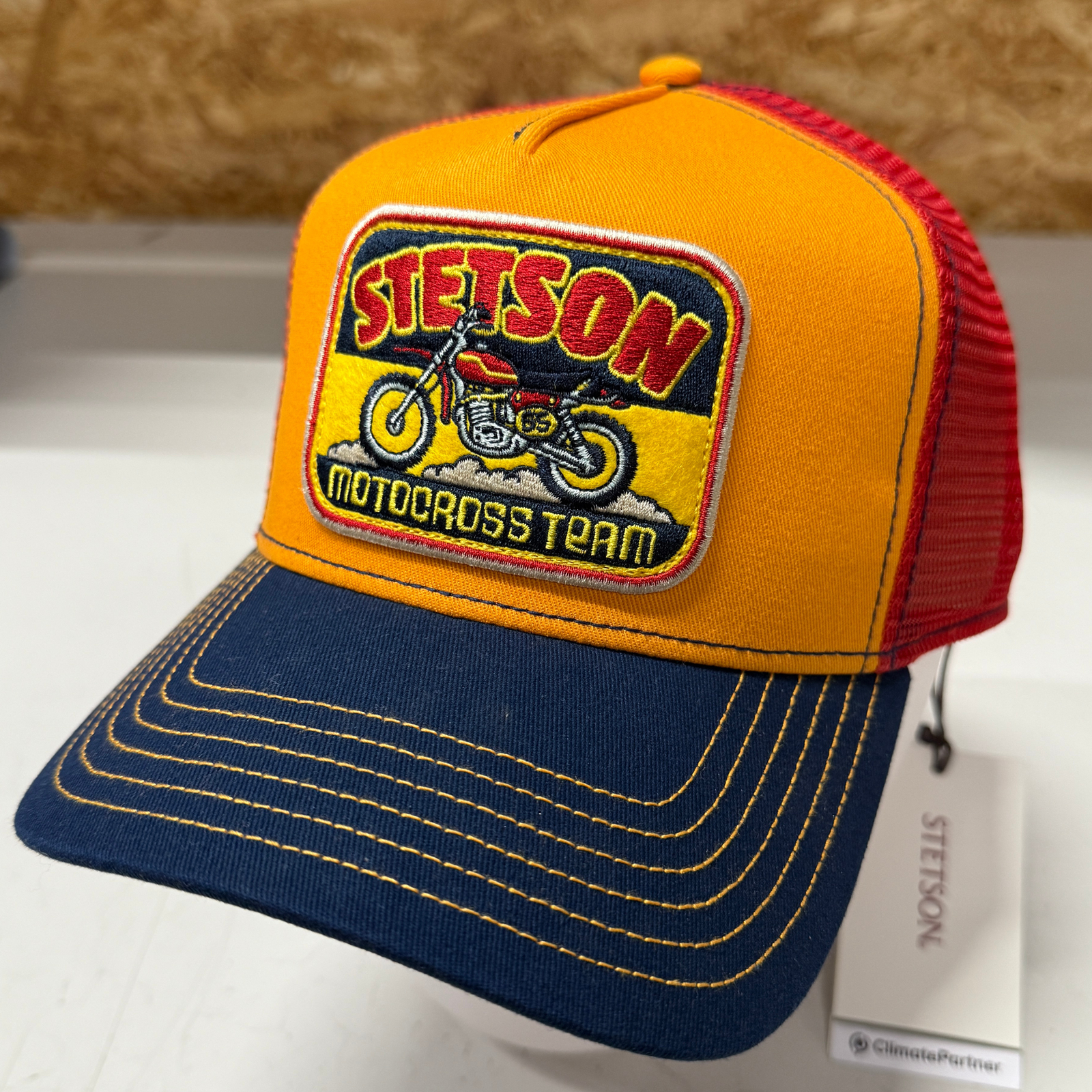 Kuvan Stetson -lippiksen lippa on sininen, takaosa punainen ja etuosa oranssi. Etuosassa on kangasmerkki jossa motocross -pyörän kuva ja teksti Stetson motocross team.