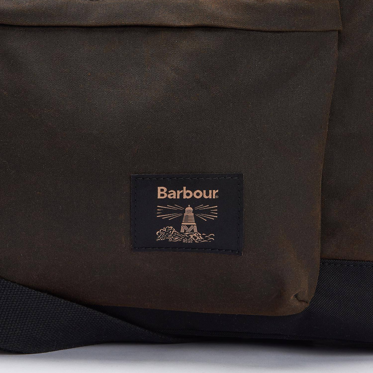 Yksityiskohta Barbour Field Waxed Holdall viikonloppulaukusta, kuvassa Barbourin majakkalogo.