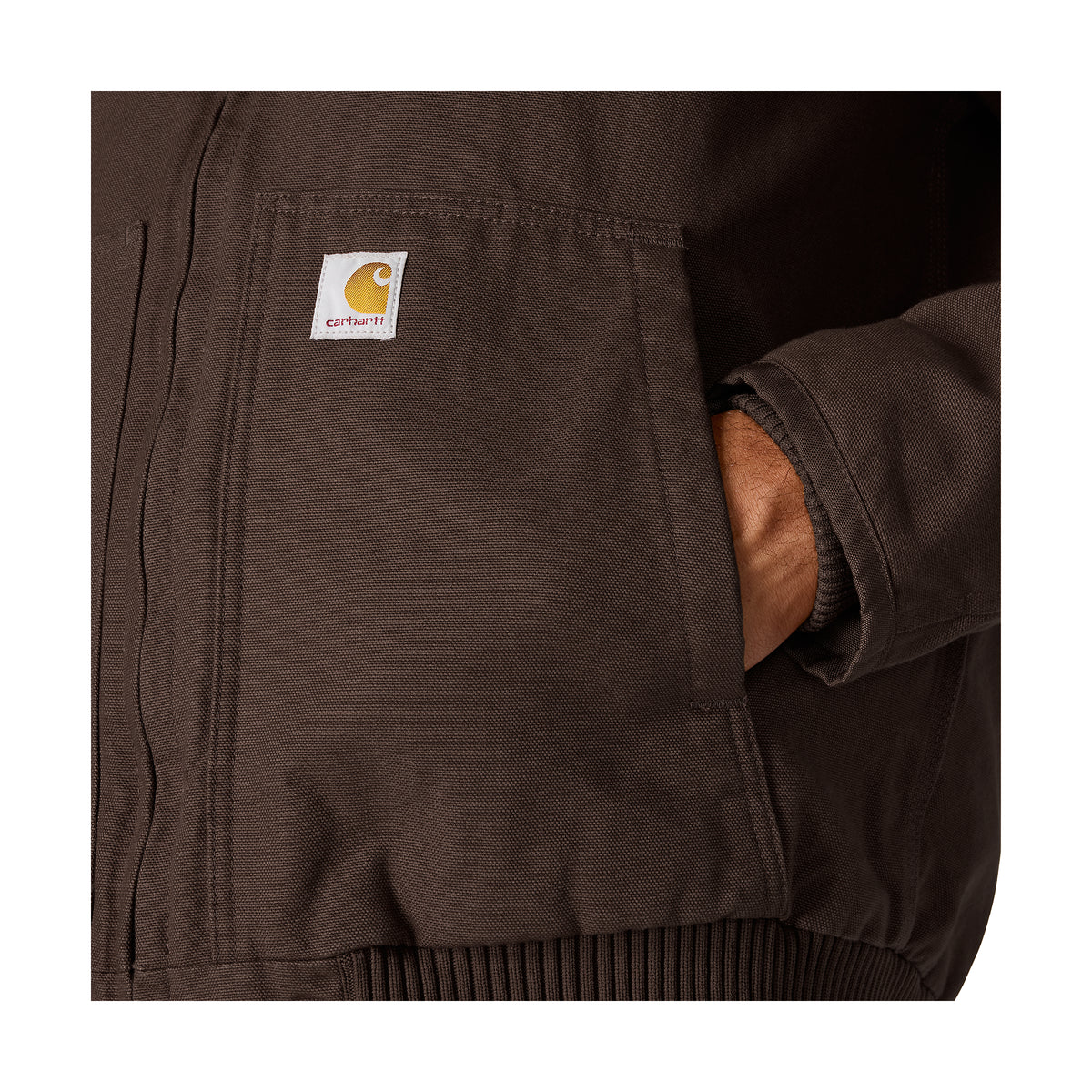 Lähikuva tummanruskean Carhartt Active Jacketin taskusta.