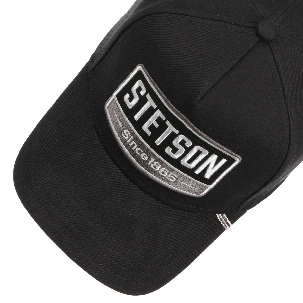 Stetson Trucker Cap 1865 musta lippis yläviistosta, kirjailtu logomerkki ja lipan raidallinen yksityiskohta.