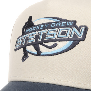 Stetson Trucker Cap Hockey -lippiksen kirjailtu Hockey Crew Stetson -logo lähikuvassa, jääkiekkoilija ja siniset yksityiskohdat.