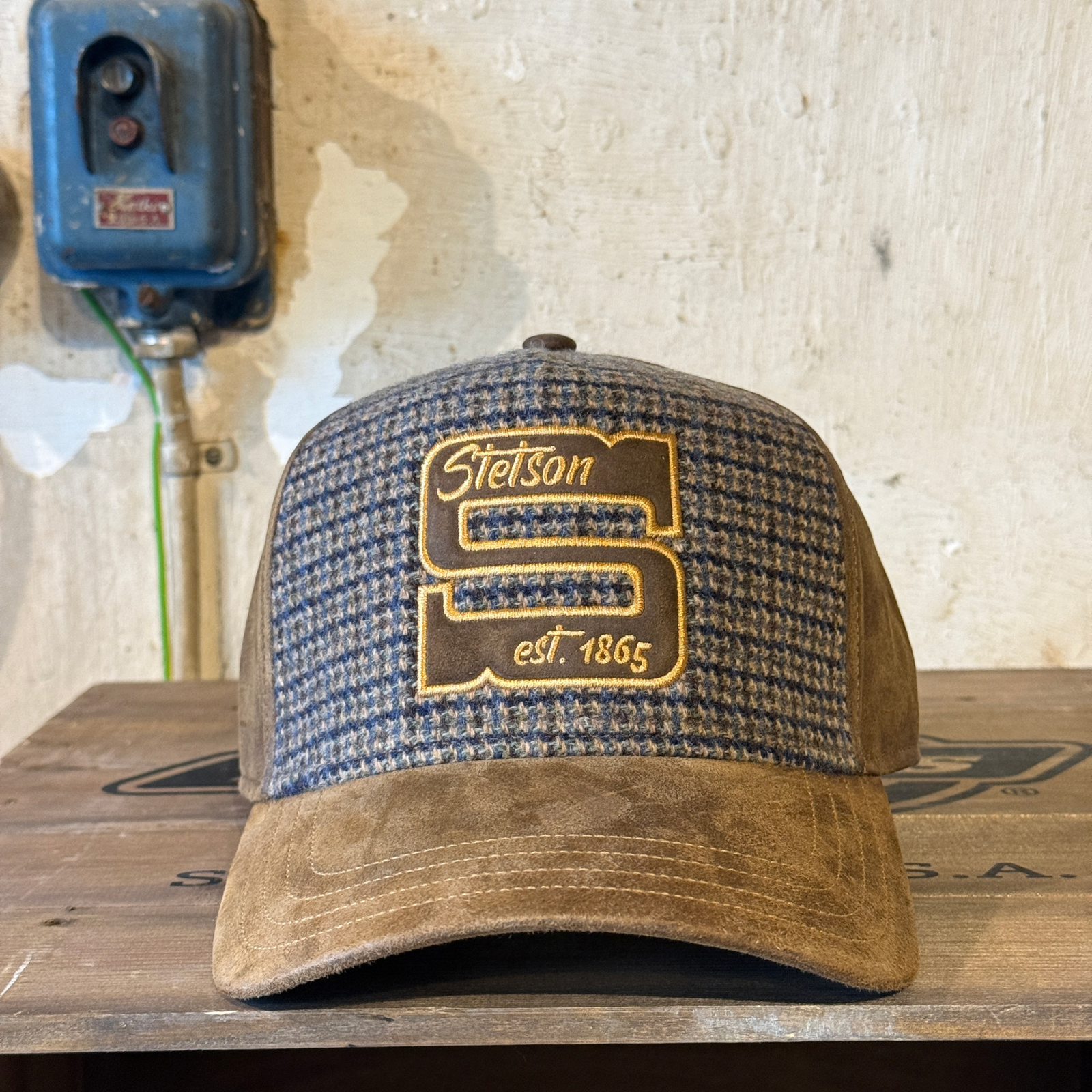 Upea Stetsonin trucker cap lippalakki, jossa ruskea mokkapinta sekä tweedkuvioitu kashmirvillainen etuosa näyttävällä brodeerauksella.
