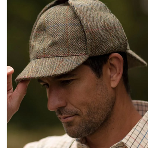 Walker & Hawkes Watson Deerstalker -tweedhattu Moss Green -värissä mallin päässä, korvaläpät ylös sidottuina.